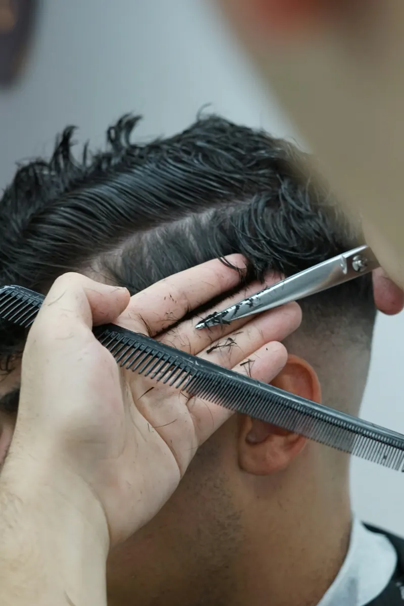 Close-up of a soft taper being cut above the ear