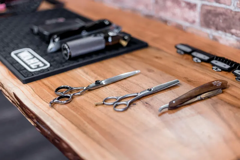 Scissors, a razor and combs laid out on a wooden counter